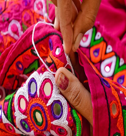 female needlework on fabric material close up view,Unidentified Tribal women sewing ethnic dresses,ahir embroidery art work close up view,Gujarat india embroidery