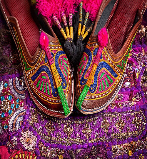 Colorful ethnic shoes and camel decorations on violet Rajasthan cushion cover on flea market in India