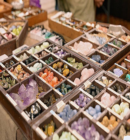 An assortment of crystals and gemstones for sale, organized in wooden boxes for alternative and spiritual healing and meditation