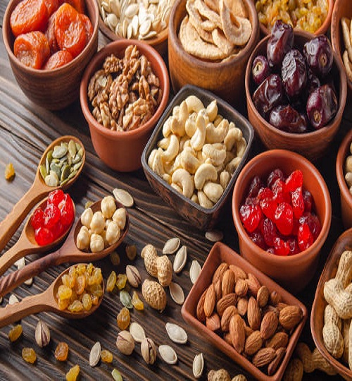 Different nuts seeds and dried fruits in bowls and spoons on wooden kitchen table